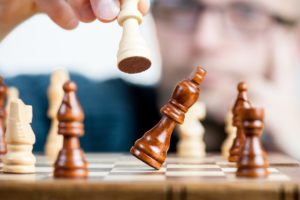 A chess piece knocks over another chess piece, an example of competition in owner marketing