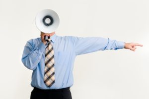 A person holds a loudspeaker in front of their face, an example of the demands placed on our attention