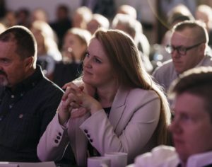 A woman looks attentively out of frame as she listens to a presentation.