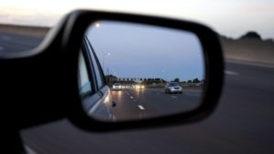 The side mirror on a car, showing the street behind the car, representing blind spots for property management business plans