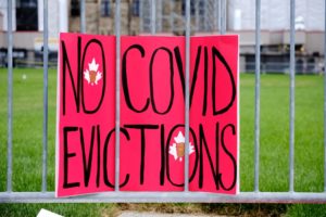 A pink sign on a fence reads No COVID Evictions, representative of the property management industry currently dealing with moratoriums.