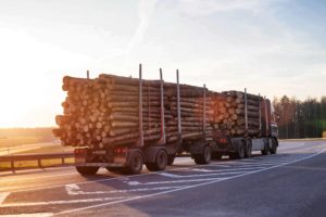 A truck carrying raw lumber, representative of the rise in lumber prices during the pandemic, and its affect on property management maintenance.